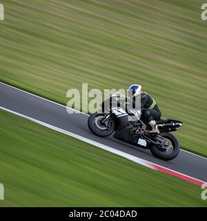 Un'inquadratura panoramica di una moto da corsa che si curva su una pista. Foto Stock