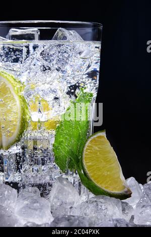 Bicchiere di acqua minerale con ghiaccio, lime e menta. Foto Stock