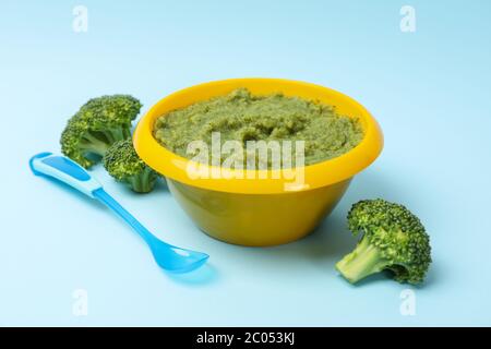 Ciotola con purea di broccoli su sfondo blu, vista dall'alto Foto Stock