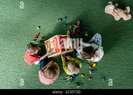 Vista dall'alto dei bambini che giocano con una casa di bambola in legno Foto Stock