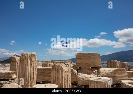 Atene Acropoli, Grecia. Bandiera greca che sventola sul palo, antica colonna rimane sullo sfondo blu del cielo, primavera giorno di sole. Foto Stock