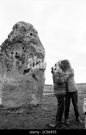 Gli amanti abbracciano - due viaggiatori New Age baciano accanto alla pietra Heel all'ingresso di Stonehenge. Wiltshire Regno Unito. Circa 1990. Foto Stock
