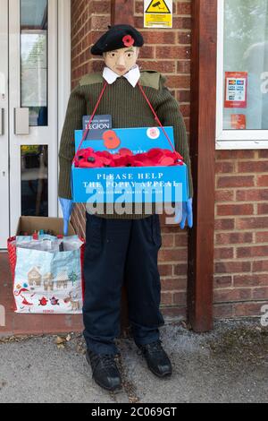 Sentiero o festival dello Scarecrow, parte delle celebrazioni del carnevale Old Basing, Hampshire, Regno Unito. Lo scaredro della Legione Britannica reale vestito da un collettore di papavero Foto Stock