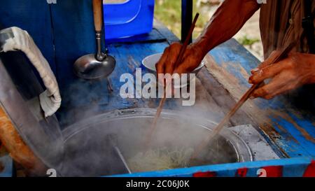 i venditori di pasta di pollo di strada preparano i menu del cibo sul carrello. Immagine a fuoco non, rumore e messa a fuoco selettiva sfocata Foto Stock