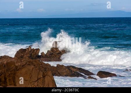 L'onda dell'oceano si sprigiona contro le grandi rocce sulla riva di Monterey Bay, California Foto Stock