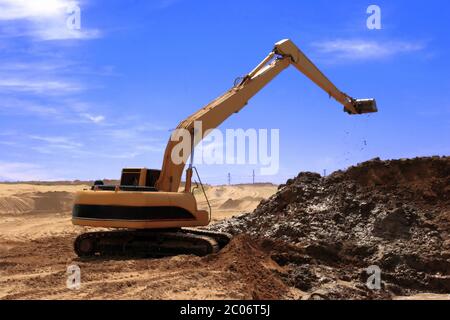 Escavatore arancione a Construction canale di irrigazione nel deserto Foto Stock