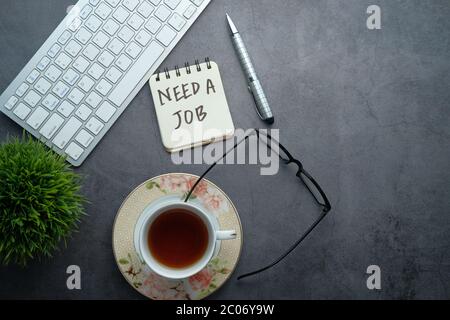 Bisogno di un lavoro, in cerca di. Testo sulla scrivania dell'ufficio con spazio per la copia. Foto Stock