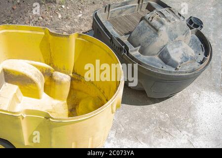 Aspirapolvere professionale dopo il lavoro. Detergente industriale case smontato. Filtro molto sporco per l'aspirapolvere domestico. Serbatoio giallo per coll Foto Stock