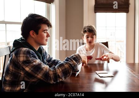 Due ragazzi adolescenti che giocano insieme le carte al tavolo da cucina. Foto Stock