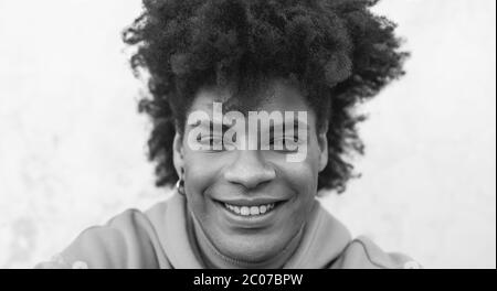 Afro sorridente uomo ritratto - misto razza giovane ragazzo con capelli ricci posa in fotocamera anteriore Foto Stock