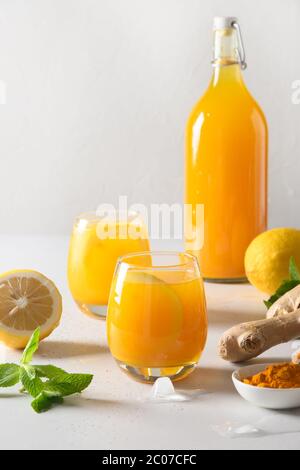 Jamu bevanda indonesiana con ingredienti naturali curcuma, zenzero, limone su sfondo bianco. Primo piano. Foto Stock