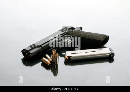 La pistola semiautomatica 1911 pesante, scaricata accanto a 8 caricatori rotondi e 4 proiettili a punta cava sciolta, è una buona scelta per la protezione domestica dalla crimpatura Foto Stock