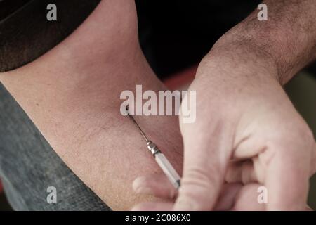 L'uomo si inietta con un piccolo ipodermico Foto Stock