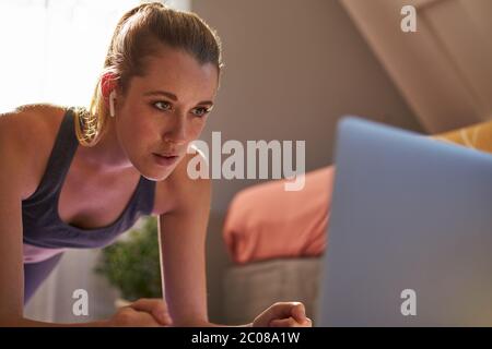 Giovane donna che partecipa a una lezione di fitness online di fronte al computer portatile. Foto Stock