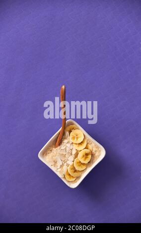 Ciotola di porridge seduta su stuoia yoga sormontata con banana e cocco. Foto Stock