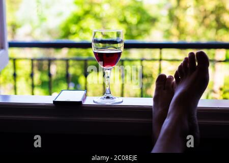 Tema vacanza. Cellulare giù e godendo la vita con un bicchiere di vino sul portico. Foto Stock