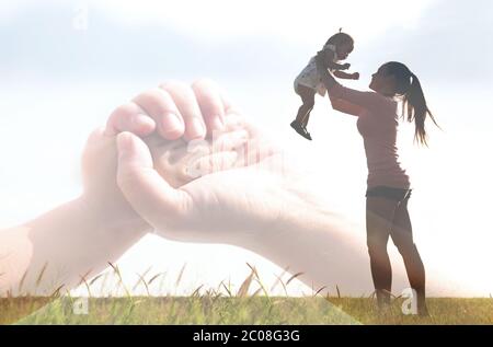 Silhouette di una mamma che tiene il suo bambino in aria, tenendo le mani. Legame di relazione familiare. Foto Stock