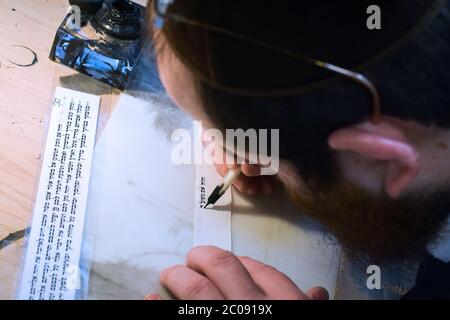 Uno scriba ebreo scrive un versetto della Torah su un piccolo pezzo di pergamena da usare nelle filacterie - tefillin. In Crown Heights, Brooklyn, . Foto Stock