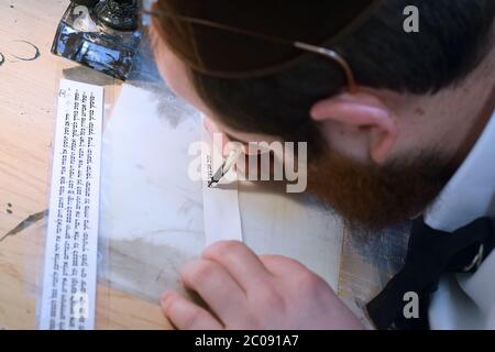 Uno scriba ebreo scrive un versetto della Torah su un piccolo pezzo di pergamena da usare nelle filacterie - tefillin. In Crown Heights, Brooklyn, . Foto Stock