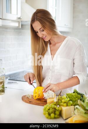 Giovane donna sorridente che cucinava verdure Foto Stock