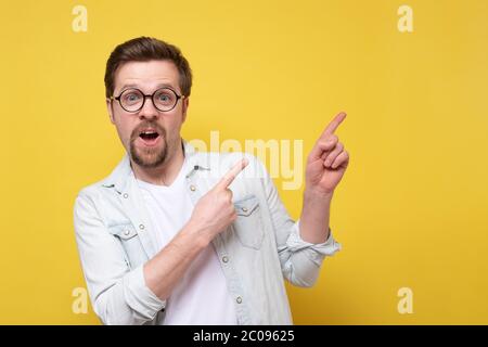 Giovane caucasico che indossa un vestito sorridente e che punta il dito da parte Foto Stock