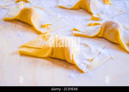 Mani della casalinga italiana che preparano pasta all'uovo per il pranzo di festa, ravioli e tortelli, pasta all'uovo ripiena di zucca e salsicce ripieno, per Foto Stock