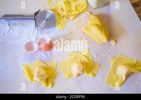 Mani della casalinga italiana che preparano pasta all'uovo per il pranzo di festa, ravioli e tortelli, pasta all'uovo ripiena di zucca e salsicce ripieno, per Foto Stock