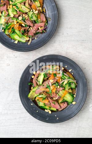 Vista dall'alto di 2 piatti di insalata di manzo asiatica. Ispirata alla cucina tailandese e vietnamita, questa insalata è fatta con verdure fresche e sane. Foto Stock