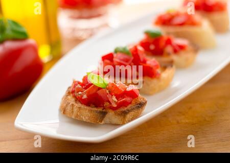 La bruschetta è un alimento italiano fatto di pomodori tritati, aglio, basilico ed erbe fresche su un pane tostato. Viene solitamente servito come snack o antipasti. Foto Stock