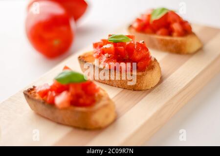 La bruschetta è un alimento italiano fatto di pomodori tritati, aglio, basilico ed erbe fresche su un pane tostato. Viene solitamente servito come snack o antipasti. Foto Stock