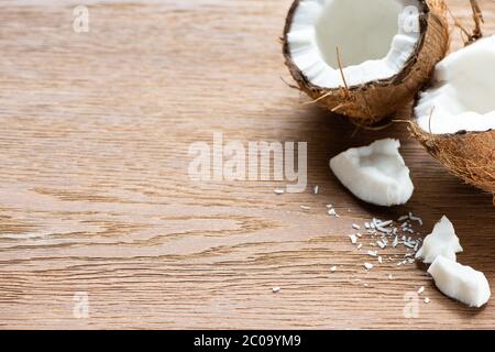 fresco gustoso noci di cocco e fiocchi di legno intero e cracked su tavolo di legno Foto Stock