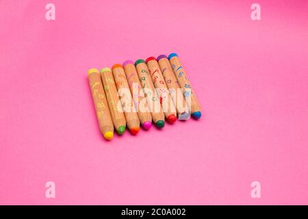 Diversi pastelli colorati in legno isolati su sfondo rosa con spazio di copia matite colorate per i bambini, primo piano Foto Stock