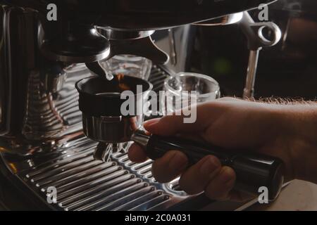 Primo piano di un barista che macina i chicchi di caffè per preparare l'espresso, primo piano macchina da caffè manuale Foto Stock