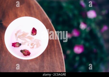 Caffè latte da asporto con barbabietola di rose e latte di cocco vegano su un tavolo di legno presso la caffetteria dell'hipster. Spazio di copia. Nuovi ordini normali, da asporto. Foto Stock