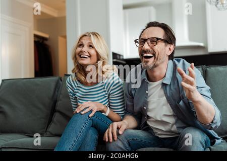 Coppia matura che ride mentre si siede sul divano Foto Stock