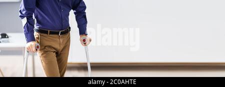 Uomo disabile camminare con grondole. Lavoratore handicappato sul posto di lavoro Foto Stock