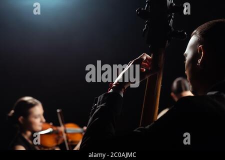 trio di musicisti professionisti che suonano su strumenti musicali su palcoscenico scuro Foto Stock