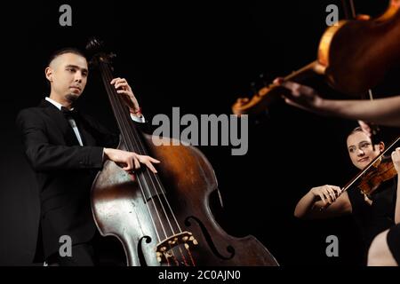 musicisti professionisti che suonano su contrabbasso e violini isolati su nero Foto Stock