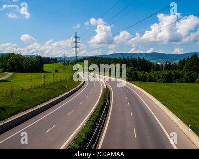 Autostrada larga a due linee con curva in giornata di sole Foto Stock