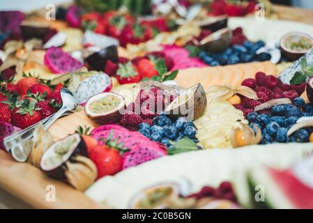 Colorato tavolo a buffet con frutta e verdura fresche. Focalizzato sui lamponi. Concetto di celebrazione, festa, compleanno o matrimonio. Foto Stock