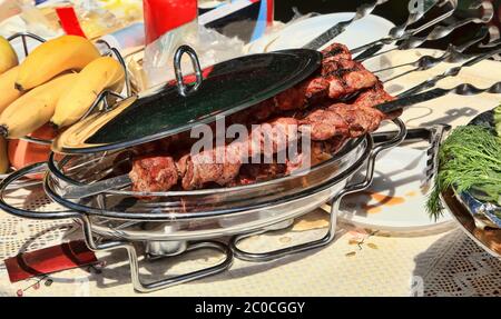 Il kebab caucasico scrisce sugli spiedini in un piatto con un coperchio per un barbecue. Messa a fuoco selettiva. Foto Stock