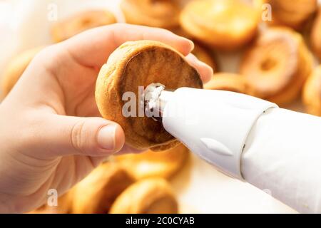 ripieno di pasticceria di profiterolle con crema utilizzando la confezione di pasticceria fatta in casa preparazione Foto Stock