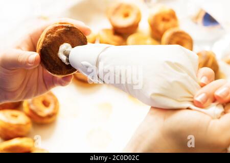 ripieno di pasticceria di profiterolle con crema utilizzando la confezione di pasticceria fatta in casa preparazione Foto Stock