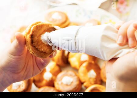 ripieno di pasticceria di profiterolle con crema utilizzando la confezione di pasticceria fatta in casa preparazione Foto Stock