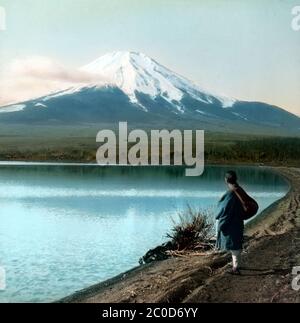 [ Giappone del 1900 - Monte Fuji ] - una vista di un monte Fuji innevato visto dal lago Yamanaka nella prefettura di Yamanashi. scivolo di vetro vintage del xx secolo. Foto Stock