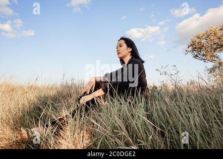 Una ragazza è seduta in un campo sull'erba Foto Stock