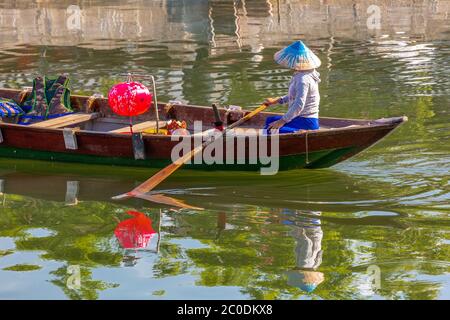Gli abitanti locali che girovagano una barca sul fiume Thu Bon nella città storica di Hoi An, patrimonio dell'umanità dell'UNESCO. Foto Stock