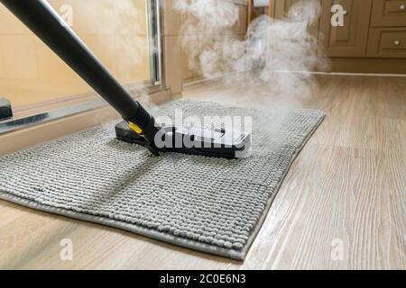 Pulizia del tappetino del bagno con un pulitore a vapore Foto Stock