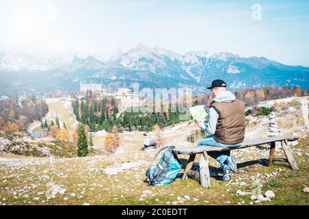 Turista con una mappa ammira le montagne, rilassandosi nella natura. Slovenia, Vogel. Foto Stock