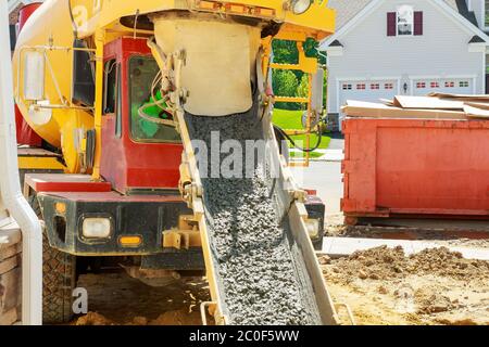 Il camion di mescolatore è cemento per versare calcestruzzo fresco in una fondazione nello sviluppo di alloggiamento Foto Stock